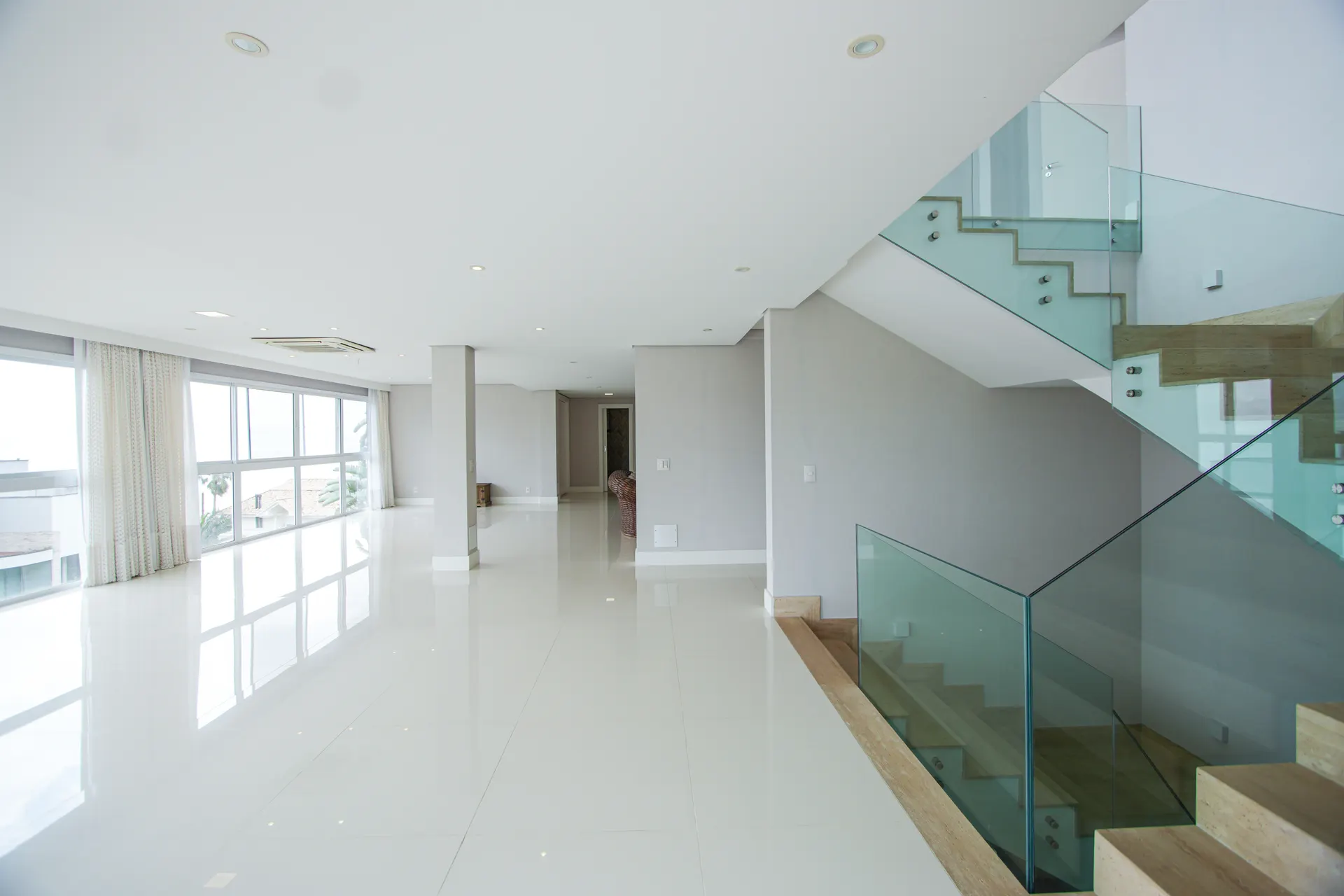 Interior amplo e iluminado com escada de vidro